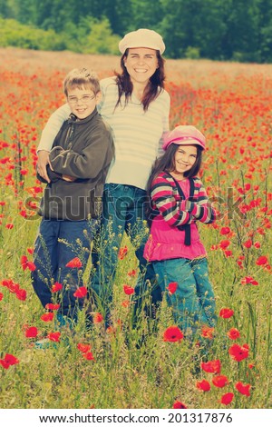 Vintage little girl, boy, mother playing on poppy field