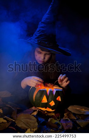 Little witch conjures up a halloween pumpkin in smoke