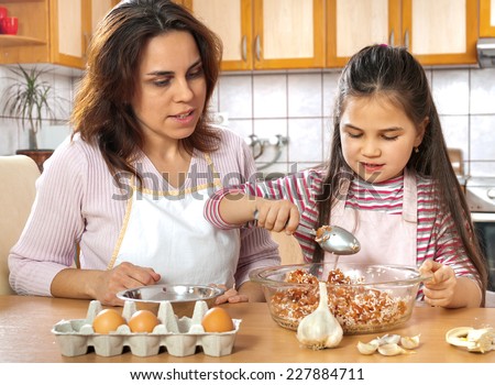 Mother teaching daughter how to prepare meat for lunch