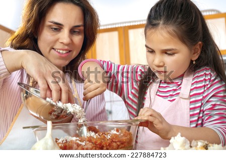 Mother teaching daughter how to prepare meat for lunch