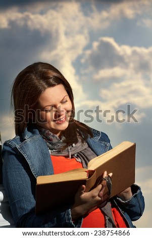 young woman standing in summer, green park reading book