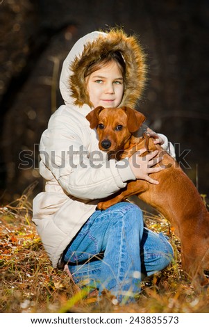 Happy little girl playing with big dog in the forest in autumn
