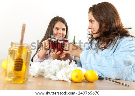Mother and daughter having tea, eating lemon, honey to heal