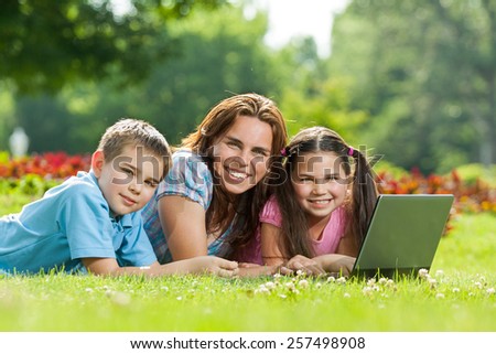Happy family having fun outdoors with a laptop computer