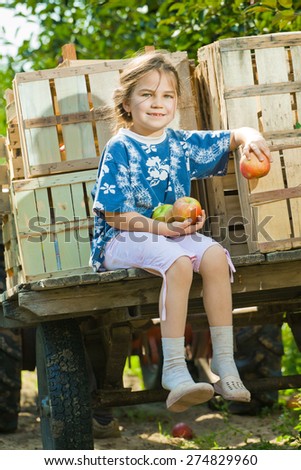Little girl with a trolley, full of apples