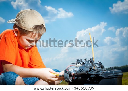 Little boy repaire the radio control car outdoor near field