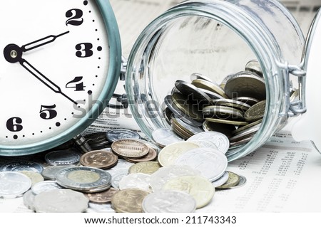 Coins, clock and open glass jar on  a data table