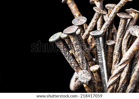 The leadership concept - The new steel nail over group of old rust nails on a black background