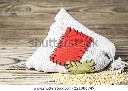 Concept of the thrift storing -Mustard seeds in the burlap sack with the patch on a wooden background