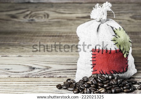 Concept of the thrift storing - Coffee beans in the burlap sack with the patch on a wooden background