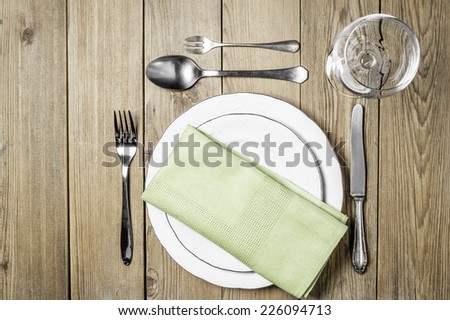 Empty plates with a napkin dining room, cutlery set and empty wine glass on a wooden background