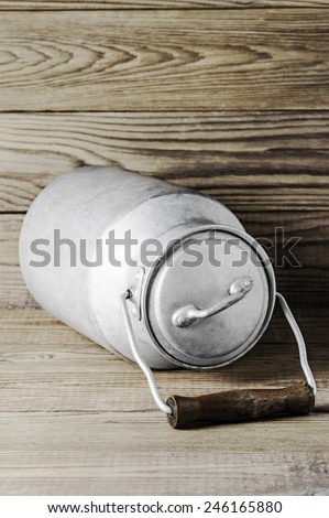Aluminum old milk can on a wooden background in the vertical format