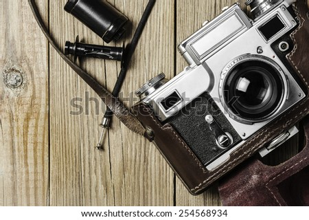 Retro camera, film cassette and release cable on a wooden background