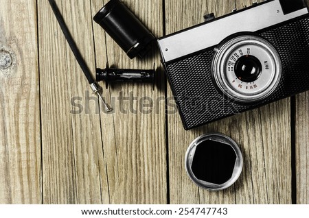 Retro camera, film cassette and release cable on a wooden background