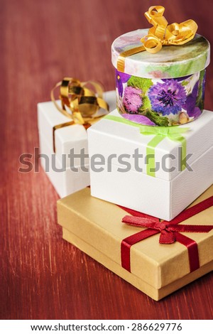 Closeup of gift boxes tied ribbons on a red wooden background