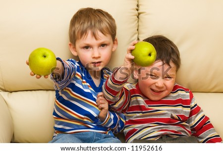 Two funny kids show an apple