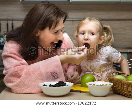 Mother with daughter  is eaten fruit in kitchen