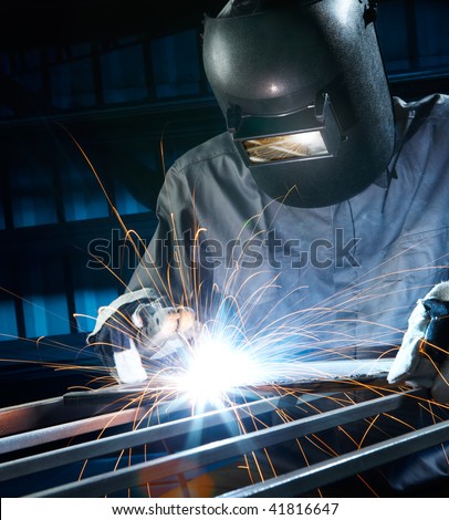 man welding with reflection of sparks on visor