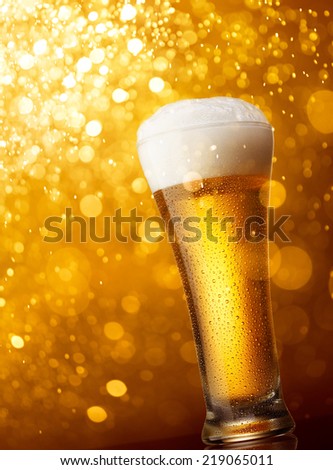 glass of beer against gold bokeh lights background