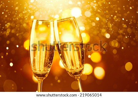 two glasses of champagne toasting against gold bokeh background