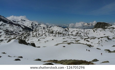 Small group of climbers walking through a snow plain on their way to Peguera mountain summit in the Pyrenees Mountains, Catalonia, Spain