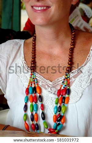 Close up of a wooden necklace worn by a cheerful young woman in Puerto Viejo, Costa Rica.