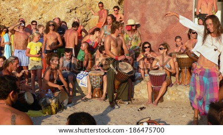 Benirras beach, Ibiza, Spain - July 23, 2006: Lots of people watching the sunset while playing drums and other instruments. This traditional celebration takes place all Sundays of July and August.