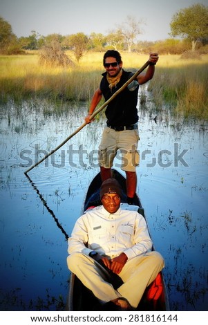 Okavango delta, Botswana - July 14th of 2012: Local guides and tourists ride traditional boats called mokoros seeking for wildlife during in amazing river safaris