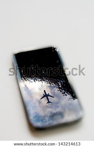 plane reflection on mobile phone with blue sky and tree
