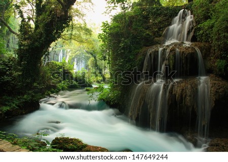 tourquoise stream landscape in forest with view of big waterfall