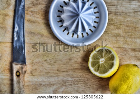 Kitchen. Lemon, fruit extractor and knife. Simple background.