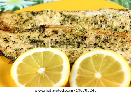 Cooked fish and lemons on yellow plate