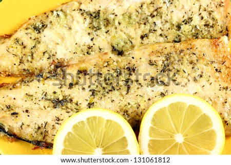 Cooked fish and lemons on yellow plate