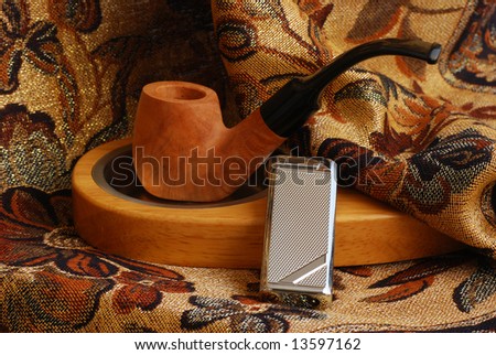 old hand carved tobacco pipe and wood and metallic ashtray and lighter