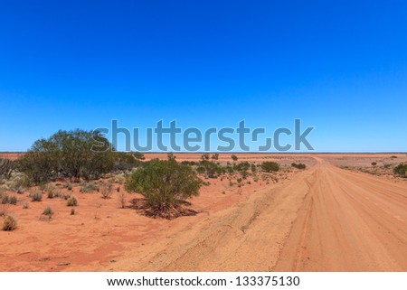 A typical Australian red dirt road with wide horizons and blue skies