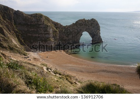Durdle Door, Dorset, England. It is a natural limestone arch on the Jurassic Coast near Lulworth in Dorset, England. The name Durdle is derived from the Old English \'thirl\' meaning bore or drill.