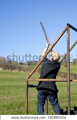 A clay shooter in the stand aiming at the clay pigeon target