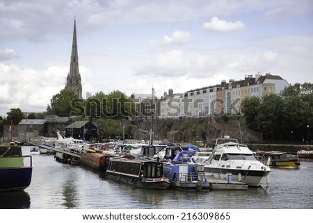 A row of colorful houses along the river in the city of Bristol, England, The church spire of St Mary, Redcliff can be seen in the distance