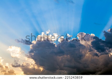 Sun rays behind the clouds in the blue sky. Religion and spirituality concept too.