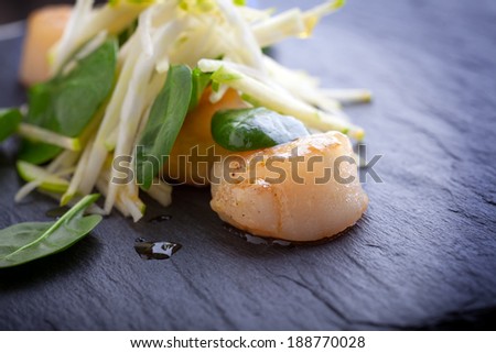 Scallop salad with apple, spinach on a stone plate