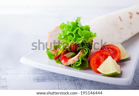 Sandwich wrap with garden salad, chicken, lettuce and tomato in a whole wheat tortilla