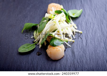 Scallop salad with apple, spinach on a stone plate