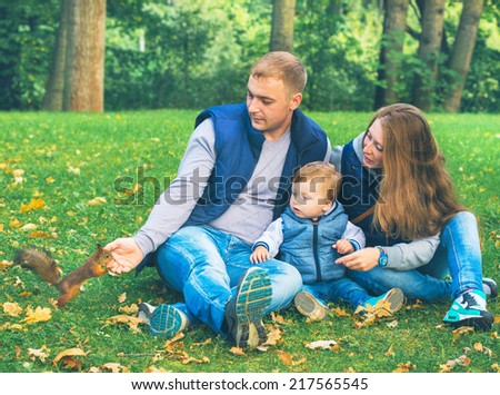 family with little child in the park feed squirrel