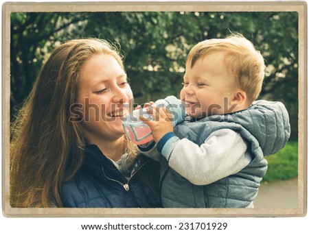 family parents with child in the park walking and playing  in same jeans clothes child eat milk