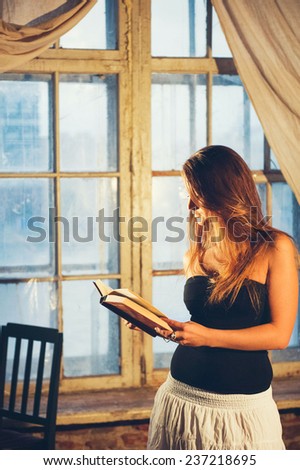 Woman with book reading   near the window in the evening