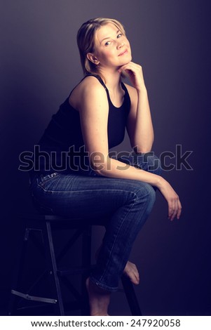 Young woman studio portrait sitting on  chair in jeans black