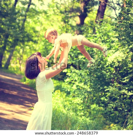 Mother with child happy family outdoors summer time in green garden playing