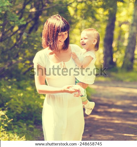 Mother with child happy family outdoors summer time in green garden playing