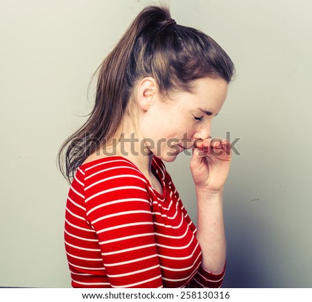 Allergy sneeze Young woman scratch nose in fashion stripes clothes hipster casual posing on light background