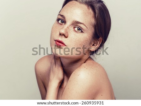 young beautiful woman with freckles portrait studio on light background hipster